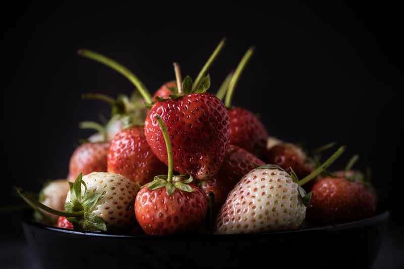 Close-up of strawberries in bowl against black background