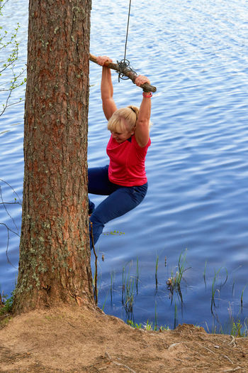 Rear view of woman swinging in lake