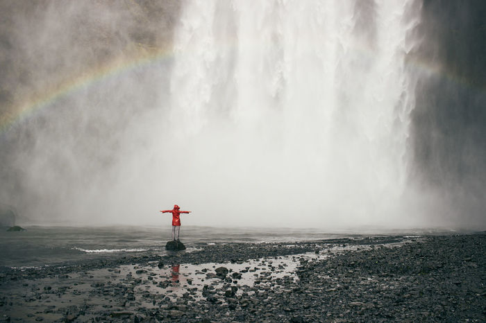 Rear view of person standing by waterfall