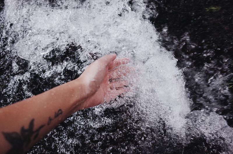 Cropped hand of woman splashing water in sea