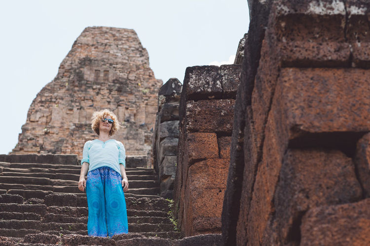 Low angle view of woman standing on steps at old ruin