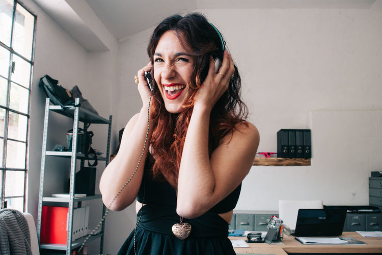 Smiling young woman with headphones in office