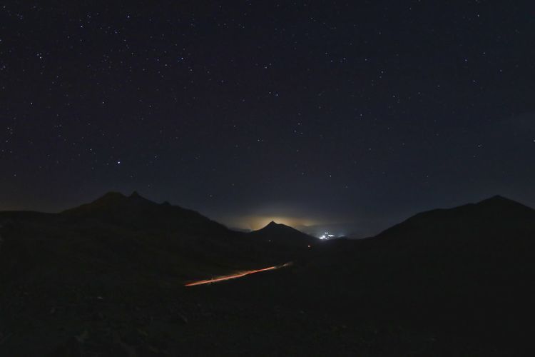 Light trail on road against mountain at night