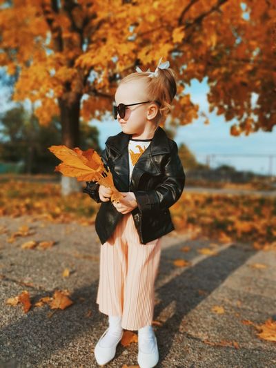 Full length of boy standing on autumn leaves