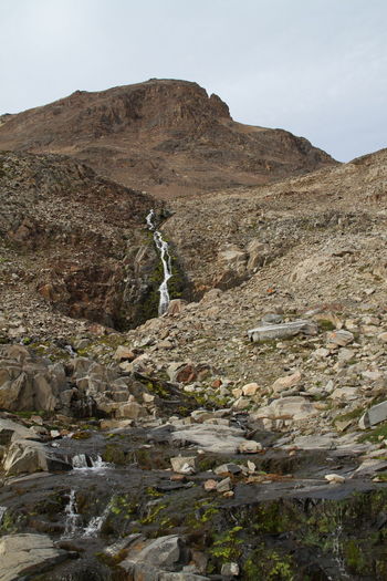 Low angle view of stream flowing through mountain against sky