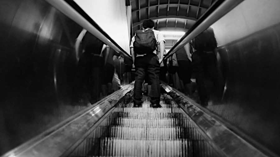 Rear view of man standing on escalator at subway station