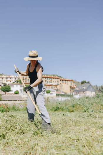 Farm worker with rake cleaning field on sunny day
