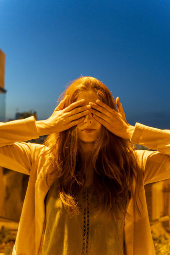 Young woman with hand on her eyes at blue hour