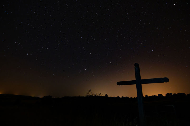 Low angle view of silhouette cross against sky at night