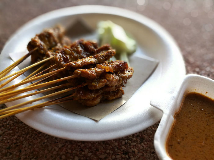 Close-up of satay by sauce on table