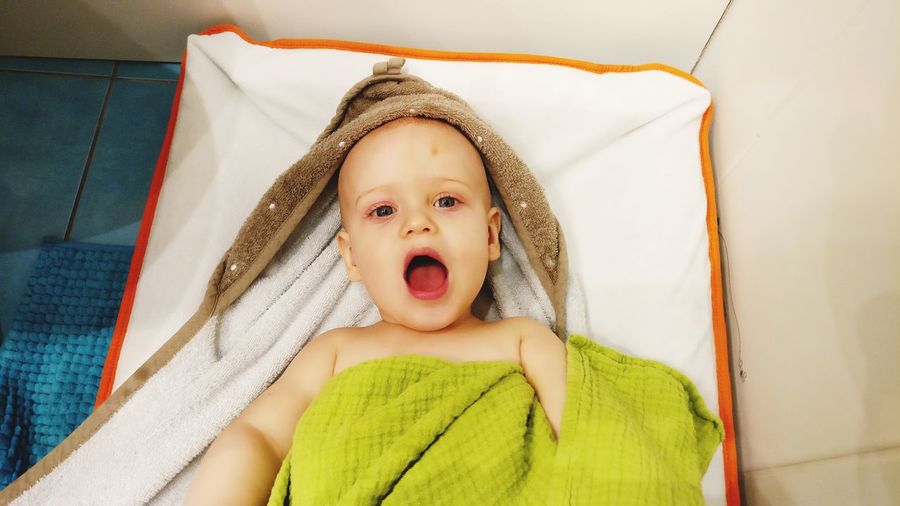 Portrait of baby boy lying on bed at home