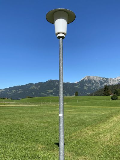 Street light on field against clear blue sky