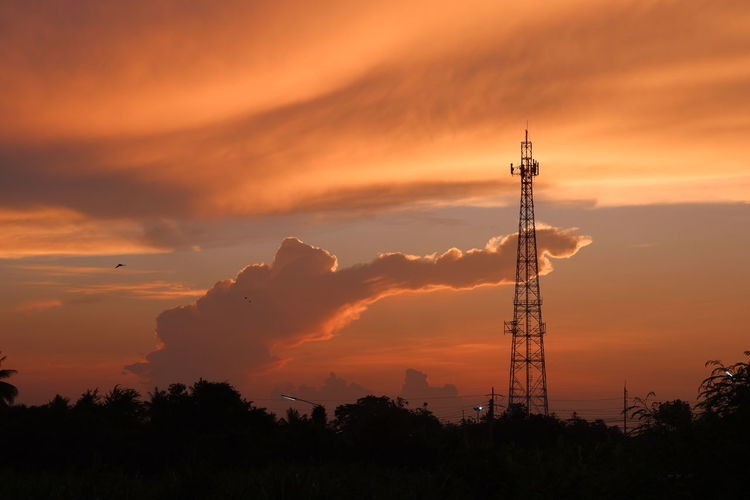Silhouette of tower against orange sky