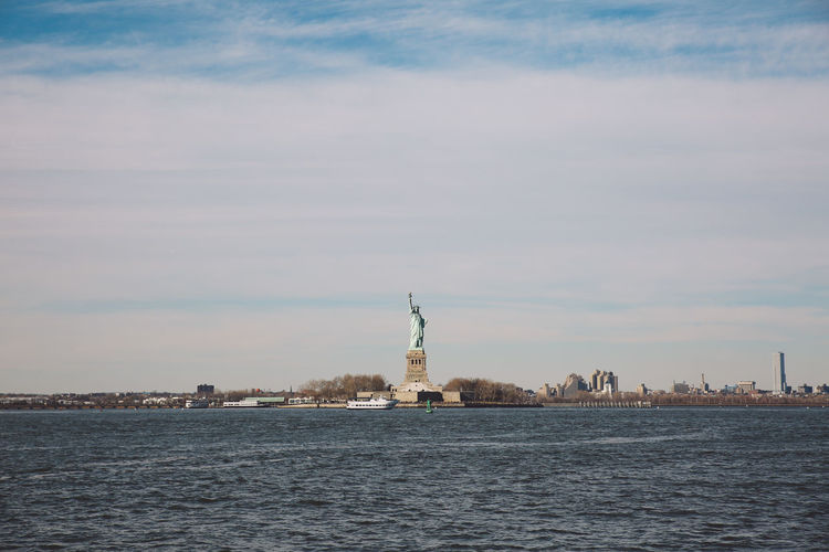 Statue of liberty by hudson river against sky