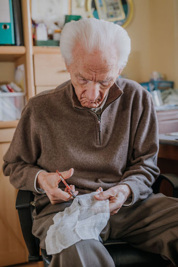 Senior man cutting bandage at home