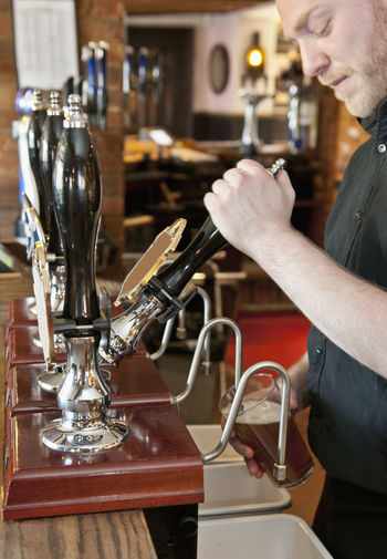 Bartender pulling beer at british pub