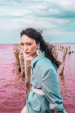 PORTRAIT OF BEAUTIFUL YOUNG WOMAN STANDING IN SEA AGAINST SKY