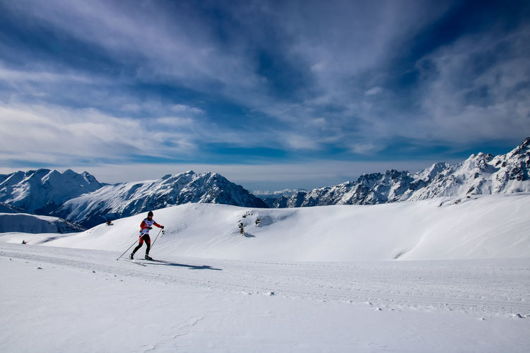 Mature man skiing on snow covered landscape against sky