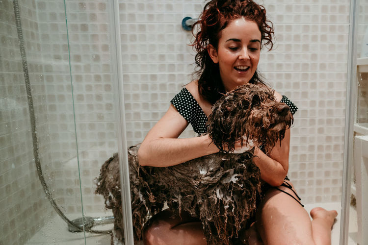 Woman washing dog in bathroom