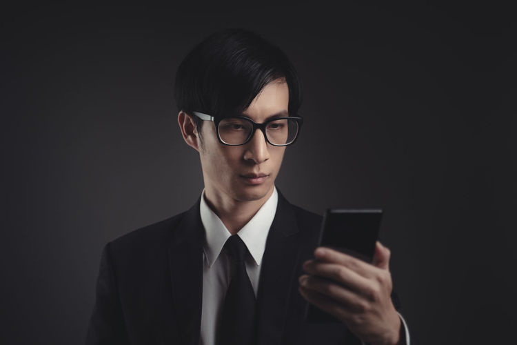Mid adult man using smart phone against black background