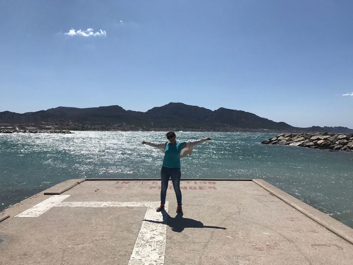 Rear view of woman standing by sea against sky