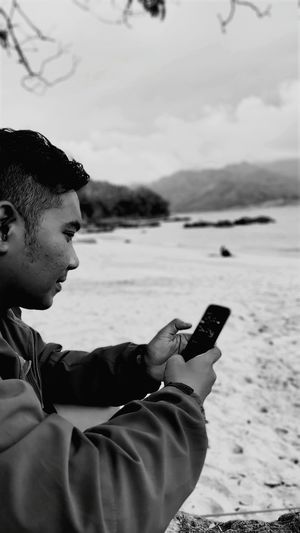 Side view of man using mobile phone at beach