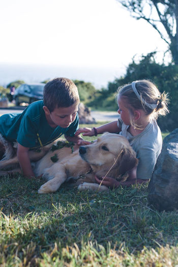 Siblings playing with dog on grassy field