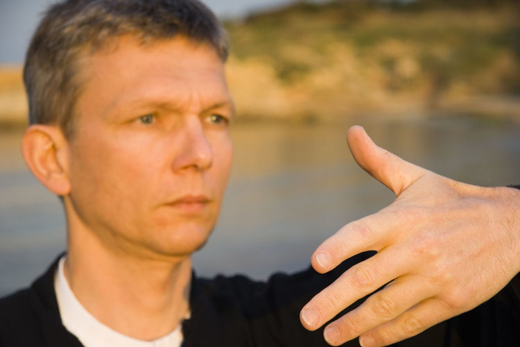 Close-up of man gesturing at lakeshore