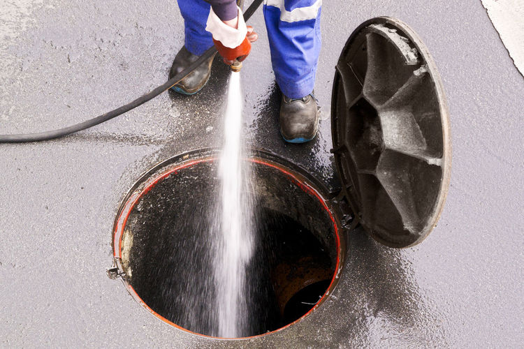 Low section of man cleaning manhole