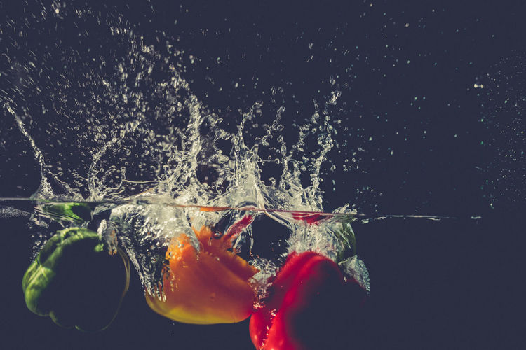 Close-up of bell peppers in water against black background
