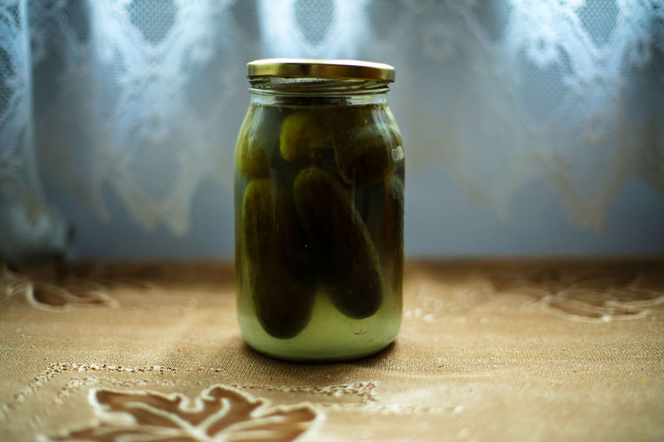 Jar of cucumber pickle on table