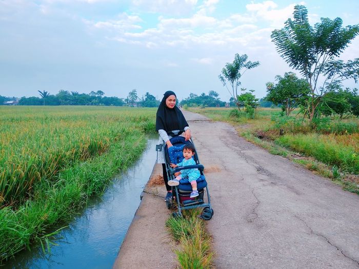 Portrait of mother with baby on road against sky