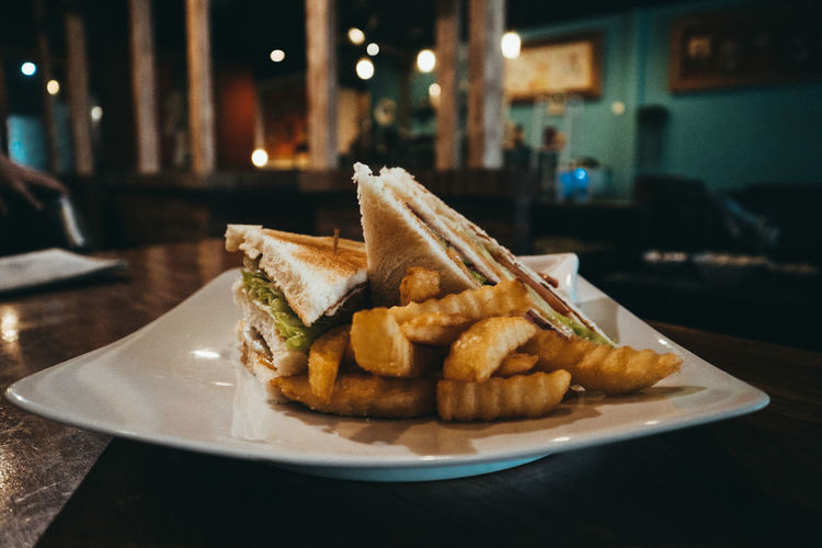 Close-up of sandwich and french fries in plate on table