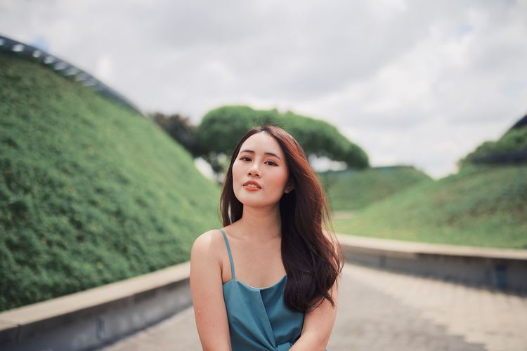Portrait of young woman with long hair on footpath