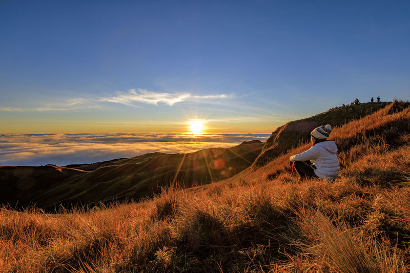 Woman watching the beautiful sun rise on the top of the mountain