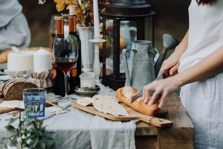 Midsection of woman cutting bread on table