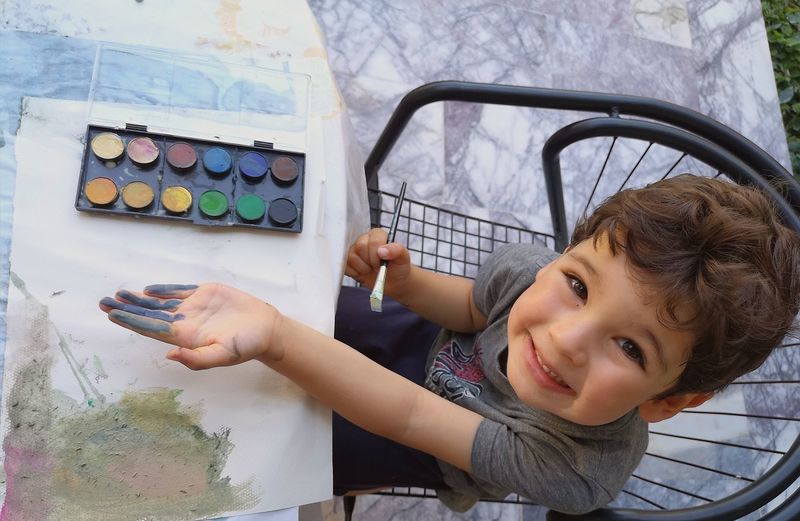 Portrait of cute boy smiling while painting with watercolour