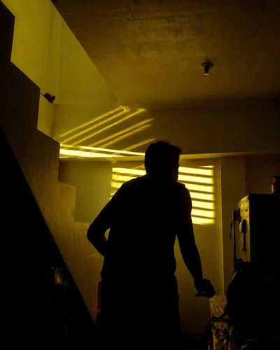 Rear view of silhouette man standing in illuminated building