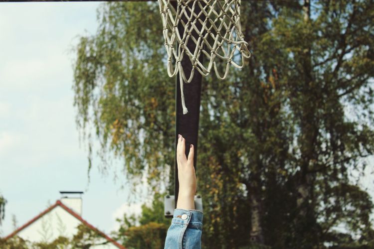 Cropped hand of teenage girl reaching  basketball hoop