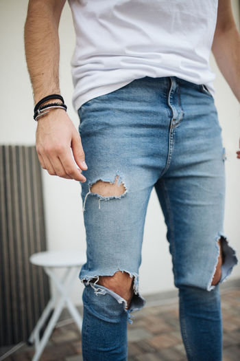 Close-up picture of attractive guy with ripped jeans.