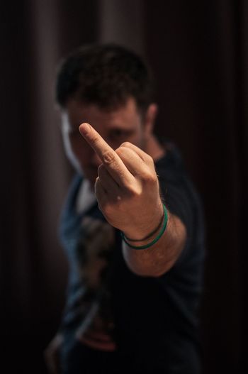 Man showing obscene gesture while standing in darkroom