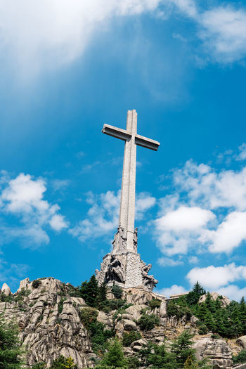 Low angle view of cross on mountain against cloudy sky