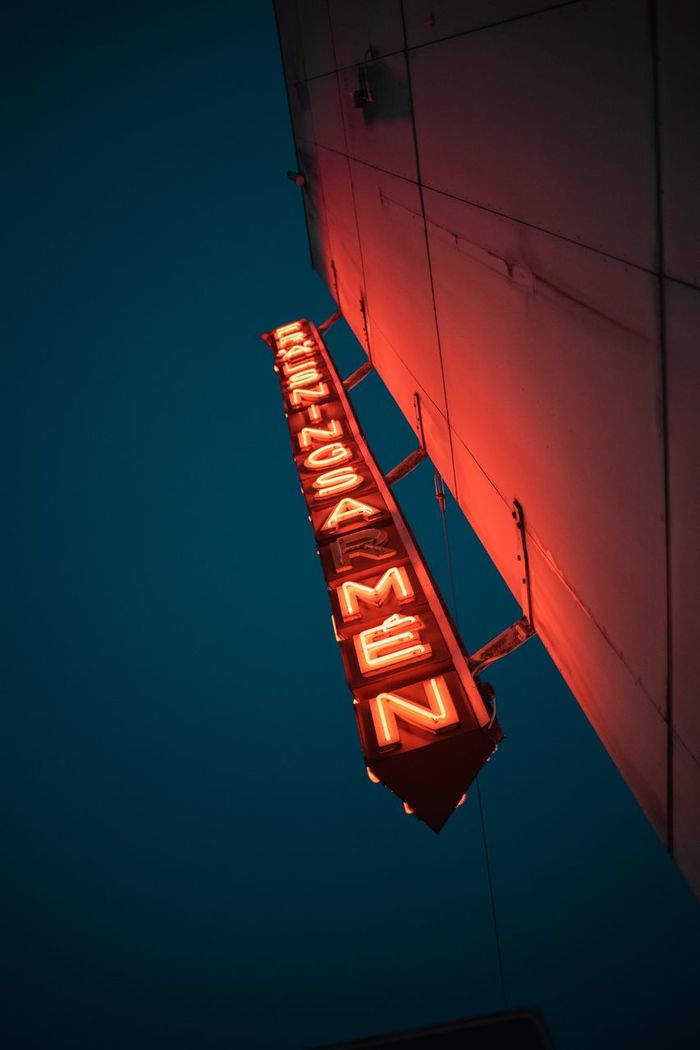 Low angle view of illuminated information sign on building against blue sky at night