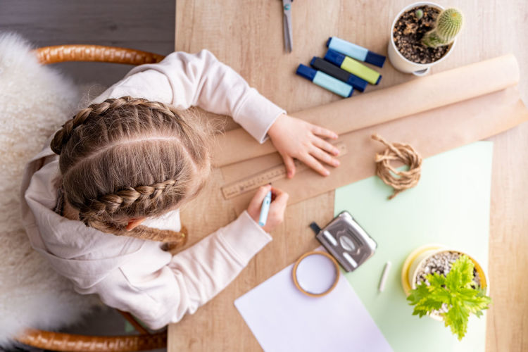 Schoolgirl or preschooler doing homework, projekt or craft, at home.