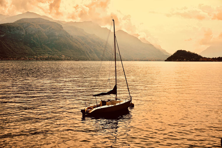 Sailboat in lake against mountains during sunset