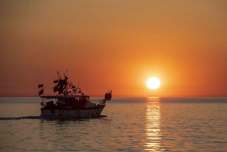 Fishing boat sailing into sunset of the coast of croatia