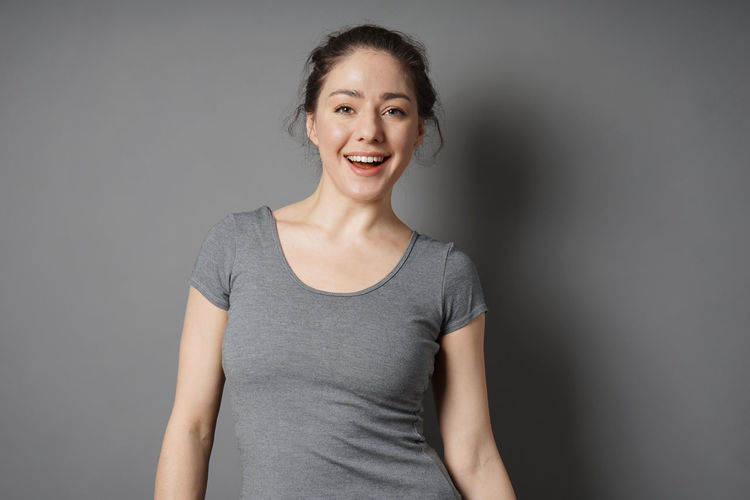 Portrait of a smiling young woman against gray background