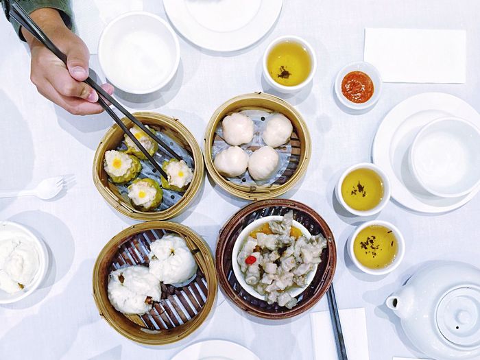 High angle view of cropped hand reaching for dumplings served in plate