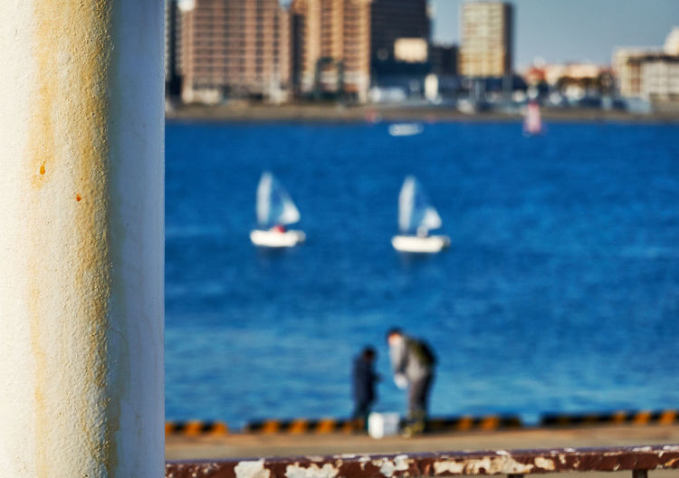 Two people standing at a harbor against sea and yacht