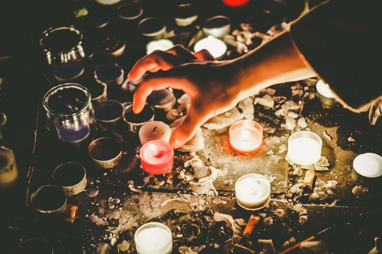 Person placing tea light candles lit as religious belief